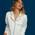 Woman wearing a white pajama set with black piping