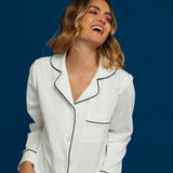 Woman wearing a white pajama set with black piping