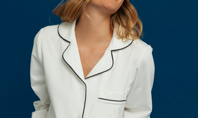Woman wearing a white pajama set with black piping
